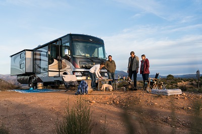 A picture of RVers outside a Type A motorhome, camping in a remote area