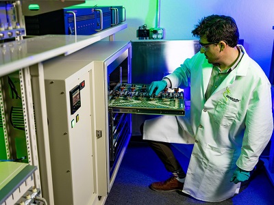 A picture of a Dragonfly Engineer in a labcoat working on a circuit board pulled out from a cabinet