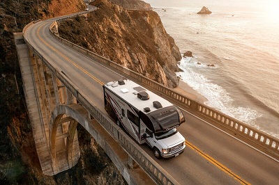 A picture of a Type C Motorhome crossing a bridge by the ocean