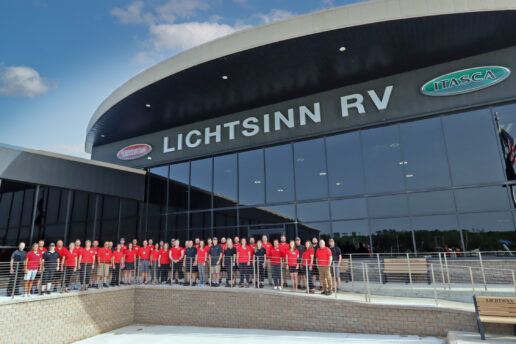 A picture of Lichtsinn RV staff wearing identical red uniform shirts outside the dealership's large, curved modernistic building
