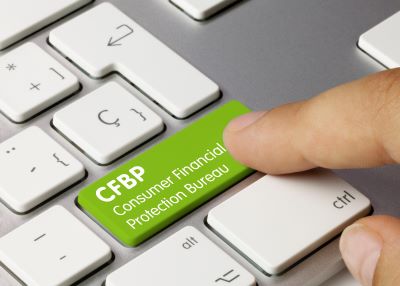 A picture of a white keyboard with a green Consumer Financial Protection Bureau key and a hand hovering over it about to push it