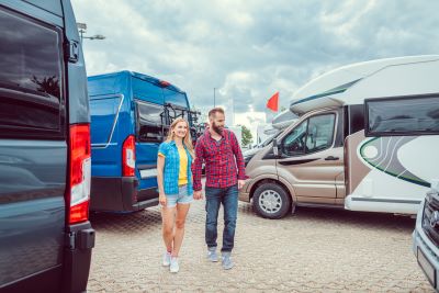 A picture of a couple RV shopping in an outdoor lot surrounded by Type B vans