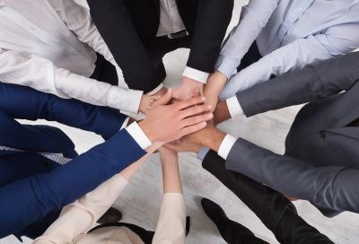 A picture of many people's hands piling on top of one another symbolizing joining or unity