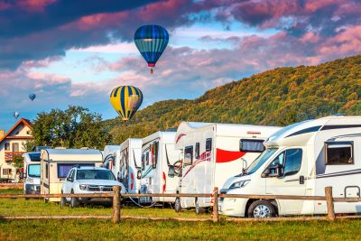 A picture of many RVs parked with hot air balloons in the background