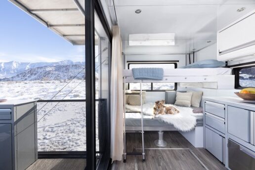 A picture of the interior of the 2024 Living Vehicle showing the bed and a mountain view through the window