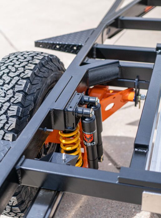 A picture of Boreas Campers standalone chassis with a closeup of the shocks and wheel