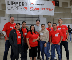 A picture of Lippert Volunteers gathered together in front of a Lippert banner in a warehouse during Volunteer Week 2023