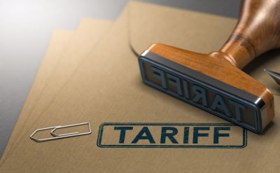 A picture of a wooden ink stamp, a manila folder with the word "Tariff" stamped on it and a paperclip