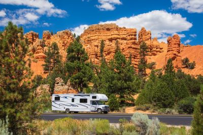 A picture of an RV in Utah on the road in front of large red rock formations