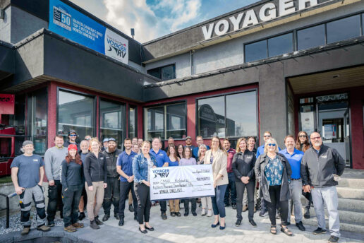 A picture of employees from Voyager RV standing outside in a large group holding a big fake check representing a large donation amount to the Canadian Mental Health Association