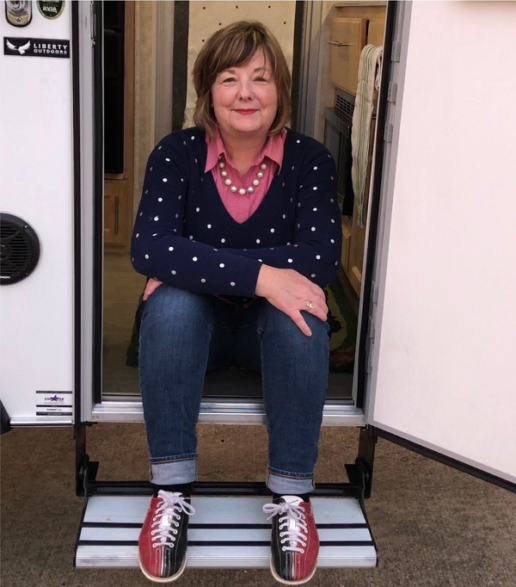 A picture of Girl Camper founder Janine Pettit sitting in the doorway of a camper 