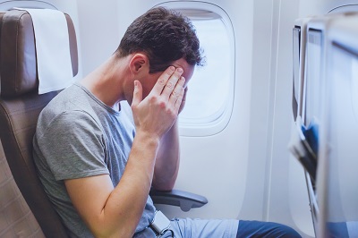 A picture of a man in an airline seat row holding his temples