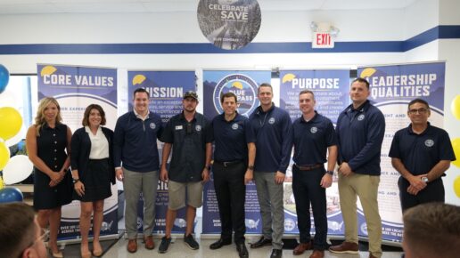 A picture of the Blue Compass RV Team showing men and women gathered inside an RV dealership at the company's new brand rollout event