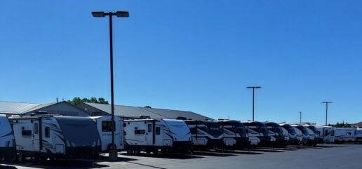 A picture of Van Boxtel RV of Green Bay Wisconsin showing a long row of RVs outside under a cloudless blue sky.