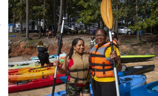 A picture of two Black women in life vests standing by canoes at the 2022 Melanated Campout event.