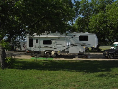 A picture of a fifth wheel at a campground with a picnic table in the foreground.