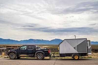A picture of a black heavy duty truck towing a sports utility vehicle beneath a grey cloudy sky