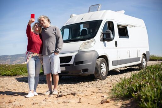 A picture of a couple taking a selfie outside their Type B motorhome, equipped with an American Power Systems second alternator.