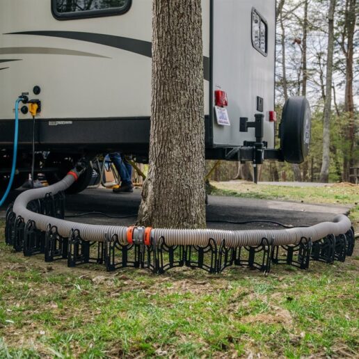 A picture of Camco's new Rhino X maximum compression sewer hose stretching from the RV to the dump site around a tree.