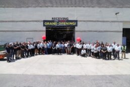 A picture of employees gathered outside the entrance to the Lance Camper Enduro plant, celebrating a ribbon-cutting for the building.