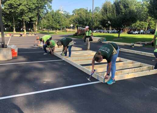 Thor Industries employees work in the parking lot of the company's headquarters to build walls for a Habitat for Humanity house.
