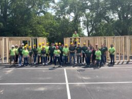 Thor Industries employees gather in the parking lot of the company's headquarters after building walls for a Habitat for Humanity house.