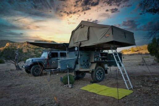 A picture of a 2023 Turtleback Trailers Expedition Trailer opened for camping with the sun about to set in the background.