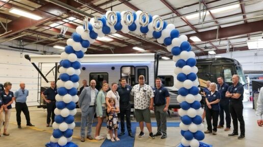 A picture of Blue Compass RV staff celebrating the 150,000th RV sold by awarding a free Jayco RV to a local family.