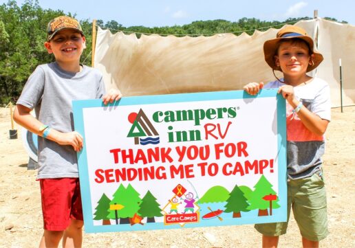 A picture of two children holding a sign thanking Campers Inn for helping them attend a Care Camps outdoors camp.