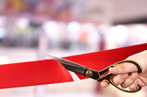 A photo of scissors cutting a red ribbon