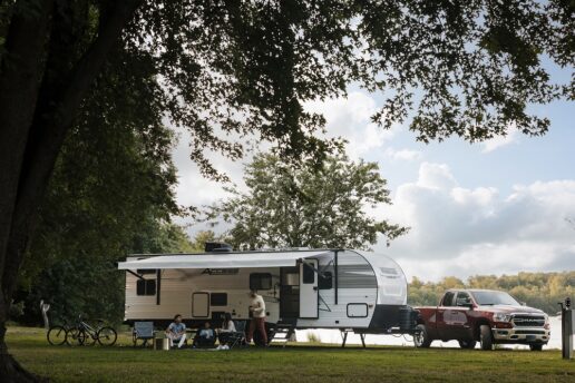 A picture of a truck towing a Winnebago Access travel trailer through the park.