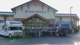 A picture of Blue Compass RV executives and employees at a ribbon-cutting outside a store finishing its brand rollout.