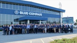 A picture of Blue Compass RV staff and executives ready to cut a ribbon outside a North Carolina dealership during Blue Compass' brand rollout.