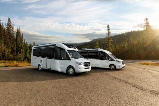 A picture of two Leisure Travel Vans motorhomes parked on pavement outside with the sun setting.