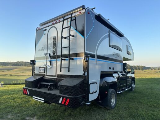 An exterior picture of the nuCamp Cirrus 920 truck camper sitting atop a truck parked on the grass.