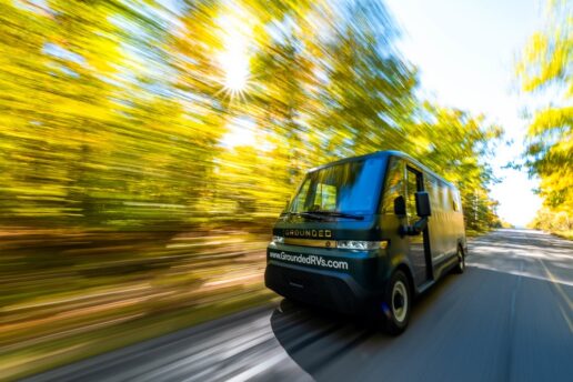 An exterior picture of the Grounded G2 all-electric motorhome driving down a tree-lined road.