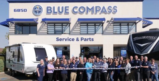 A picture of Blue Compass RV employees at a ribbon-cutting outside a dealership.