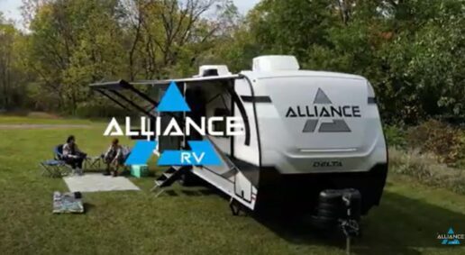 A screenshot from a video with Alliance RV's Delta travel trailer parked at a campsite with a family sitting outside on a sunny day.