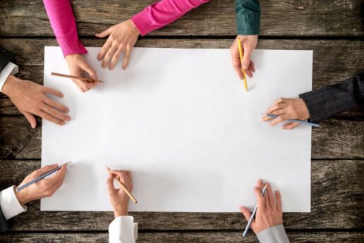 A picture of hands writing on a blank piece of paper.