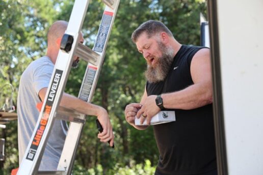 A photo of two men working to install a solar power system on an RV.