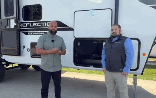 A photo of two people standing outside the Grand Design Reflection 100 Series 32BH fifth wheel.