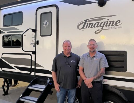 A photo of two Windish RV employees in front of a Grand Design Imagine travel trailer.