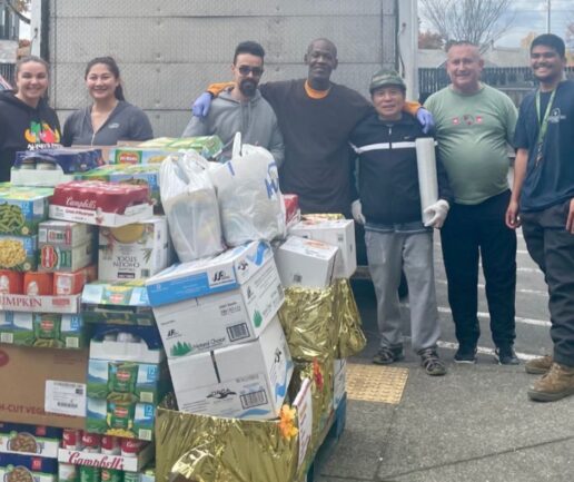 Volunteers stand outside of a box truck with pallets full of donated food.