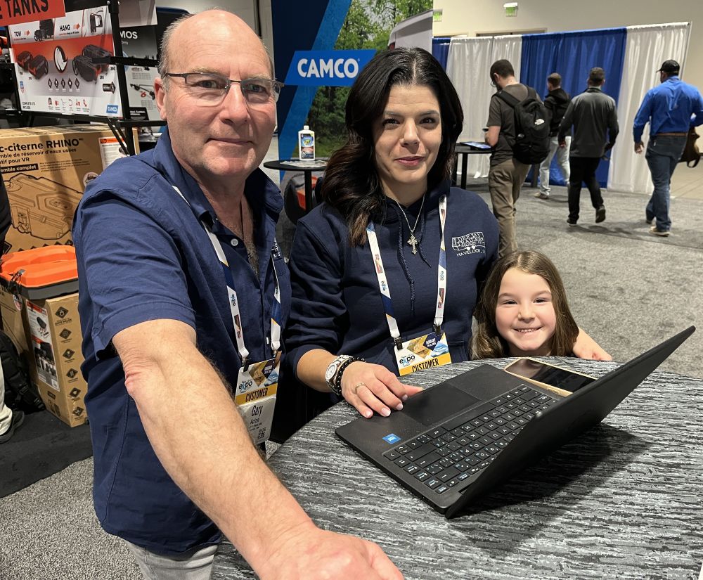 A photo of two adults and a child in front of a computer at the NTP-Stag Expo.