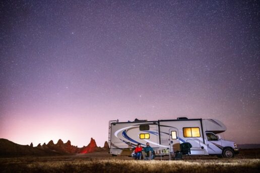 A couple star gazing outside of their Type-B motorhome.