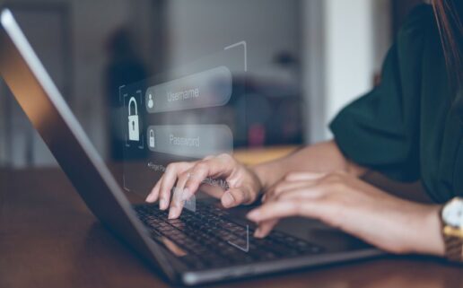 A stock photo of a person at a laptop entering a username and password.